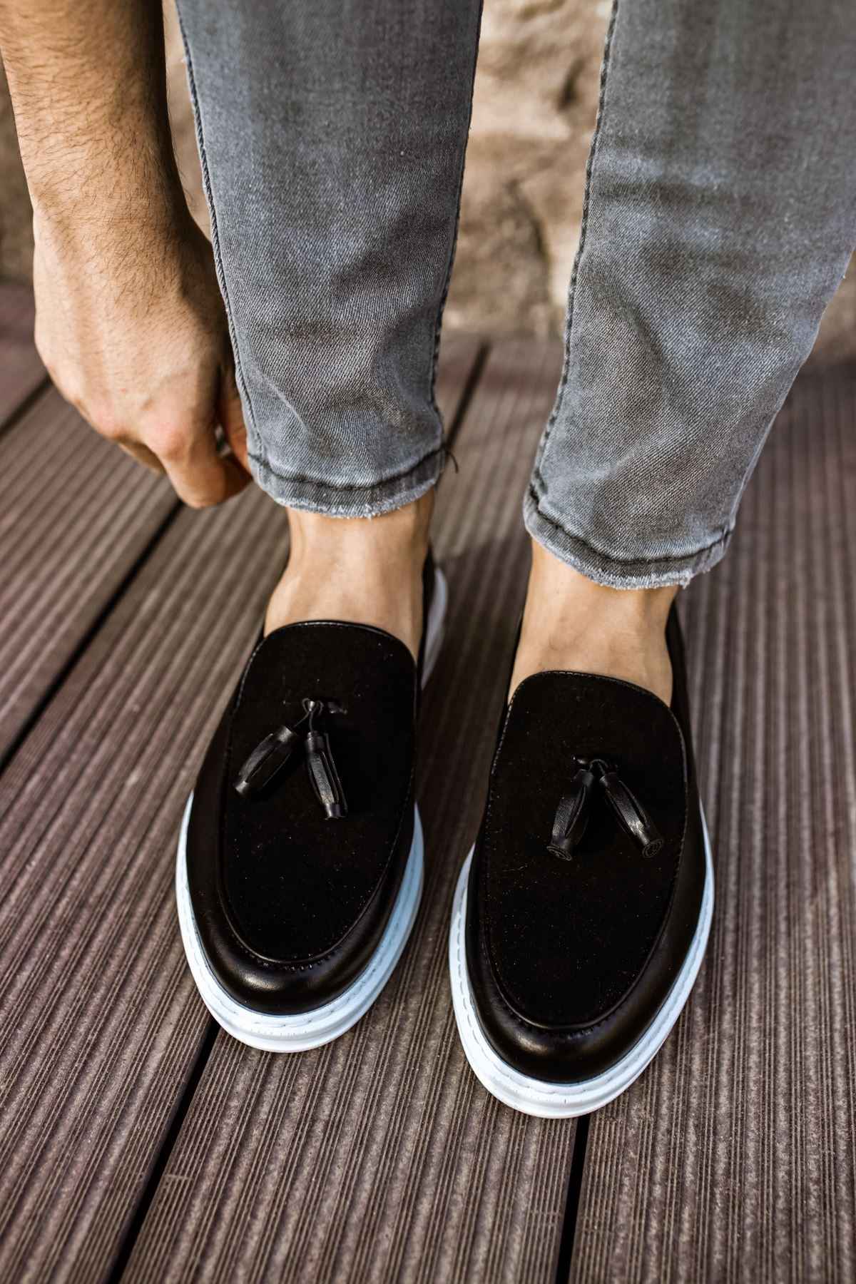 Black tassel loafers, front view with white sole and curved uppers