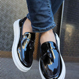 Men's black patent leather loafers with glossy strap and white sole, top angle