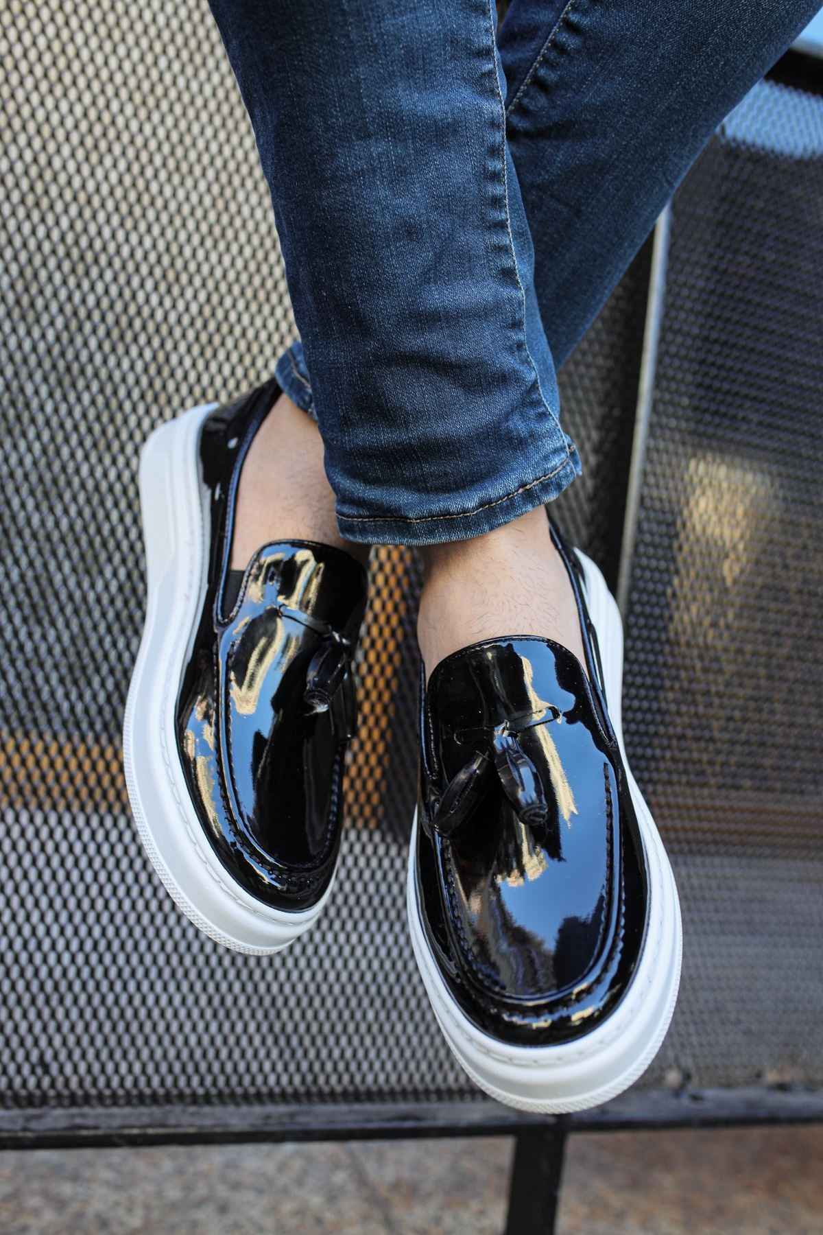 Men's black patent leather loafers with glossy strap and white sole, top angle