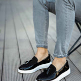 Black patent leather loafers with tassel detail and white sole, side view