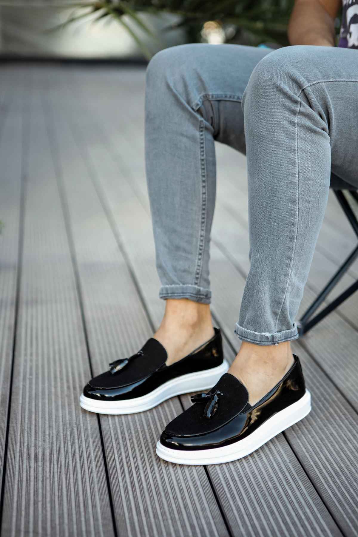 Black patent leather loafers with tassel detail and white sole, side view
