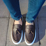 Brown loafers with tassel fronts and white soles, viewed from front.
