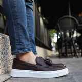 Brown slip-on loafers with tassel detail and thick white sole.