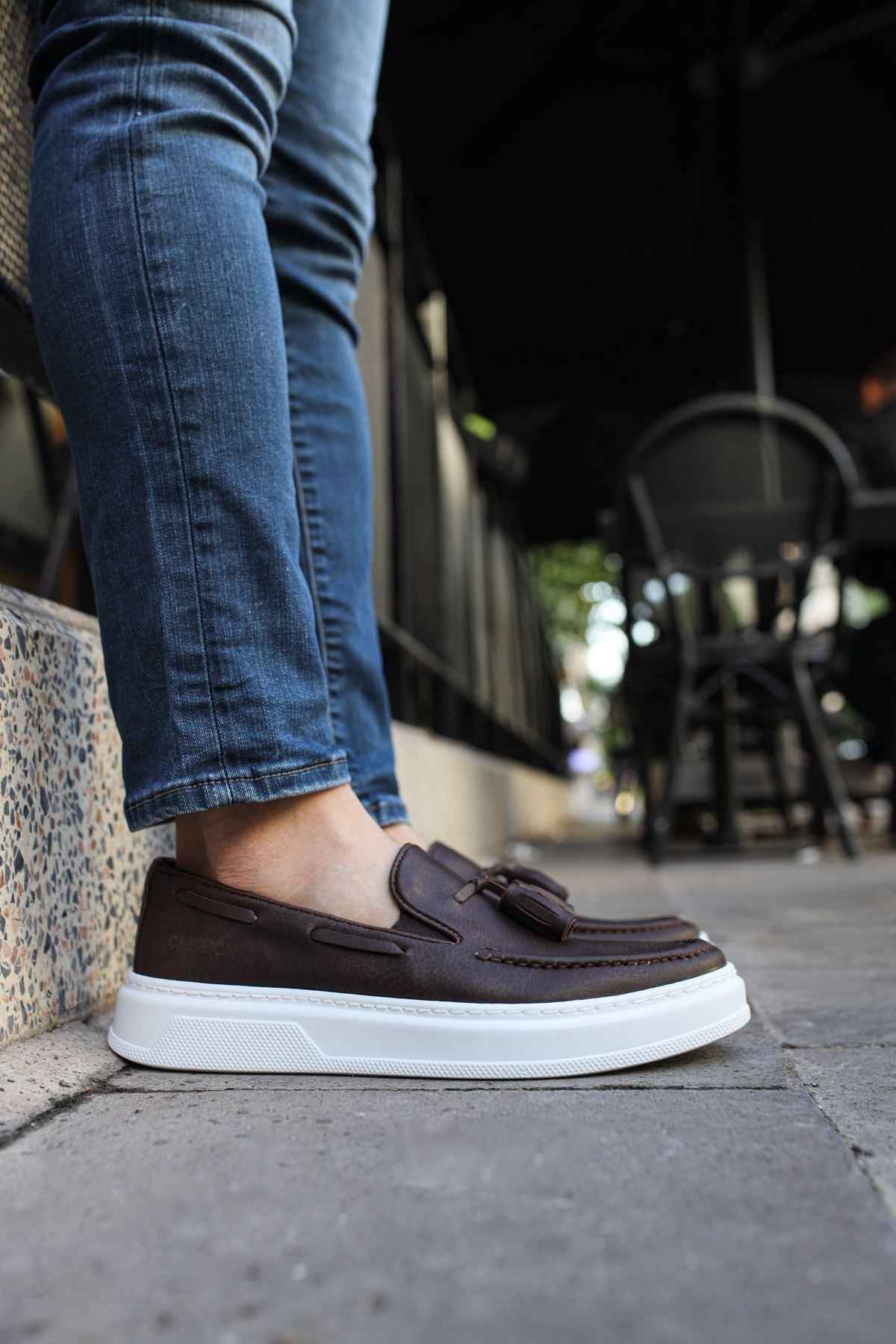 Brown slip-on loafers with tassel detail and thick white sole.