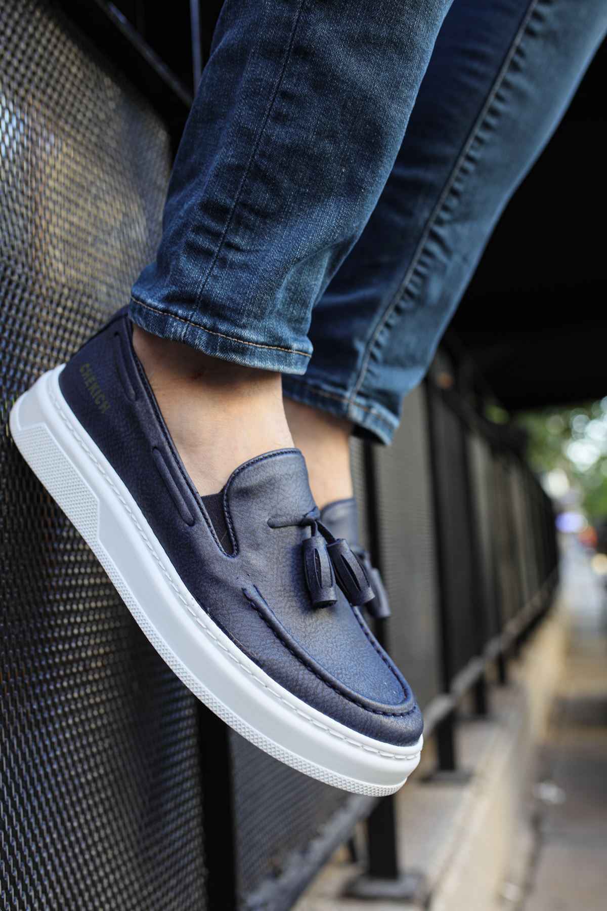 Navy suede slip-on loafers with tassel detail and thick white sole trim