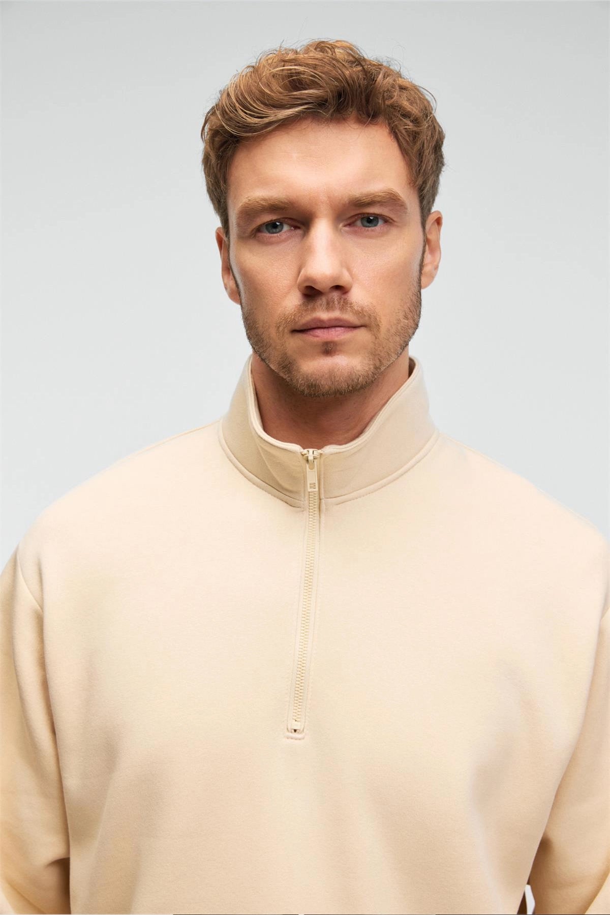 Men's cream half-zip stand-collar sweatshirt, close-up of zipper and collar
