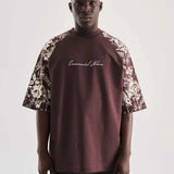 Brown oversize T-shirt with floral print sleeves and centered script graphic