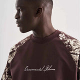 Brown oversize T-shirt close-up with script logo and floral print on shoulder