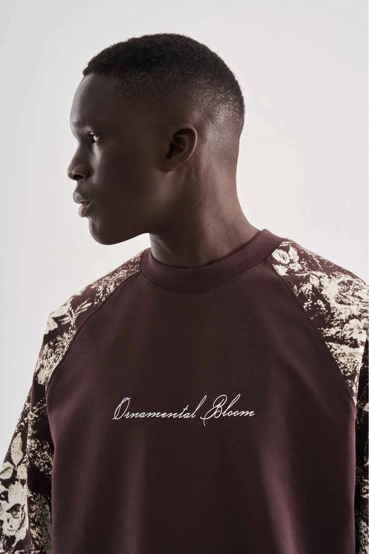 Brown oversize T-shirt close-up with script logo and floral print on shoulder