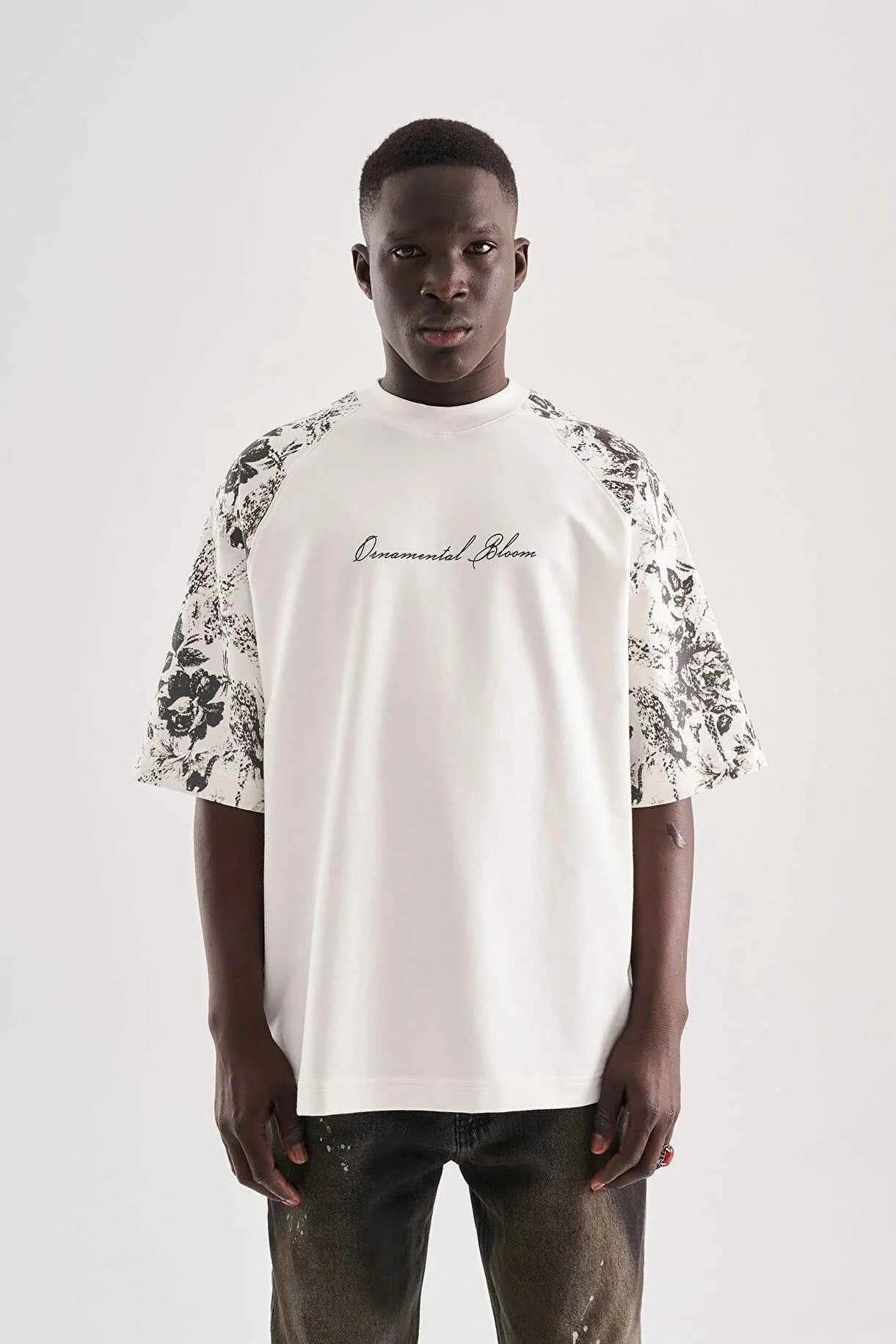 White oversized T-shirt with black floral print sleeves and small chest cursive