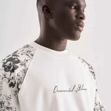 White oversized T-shirt in profile with black floral shoulder print and chest text