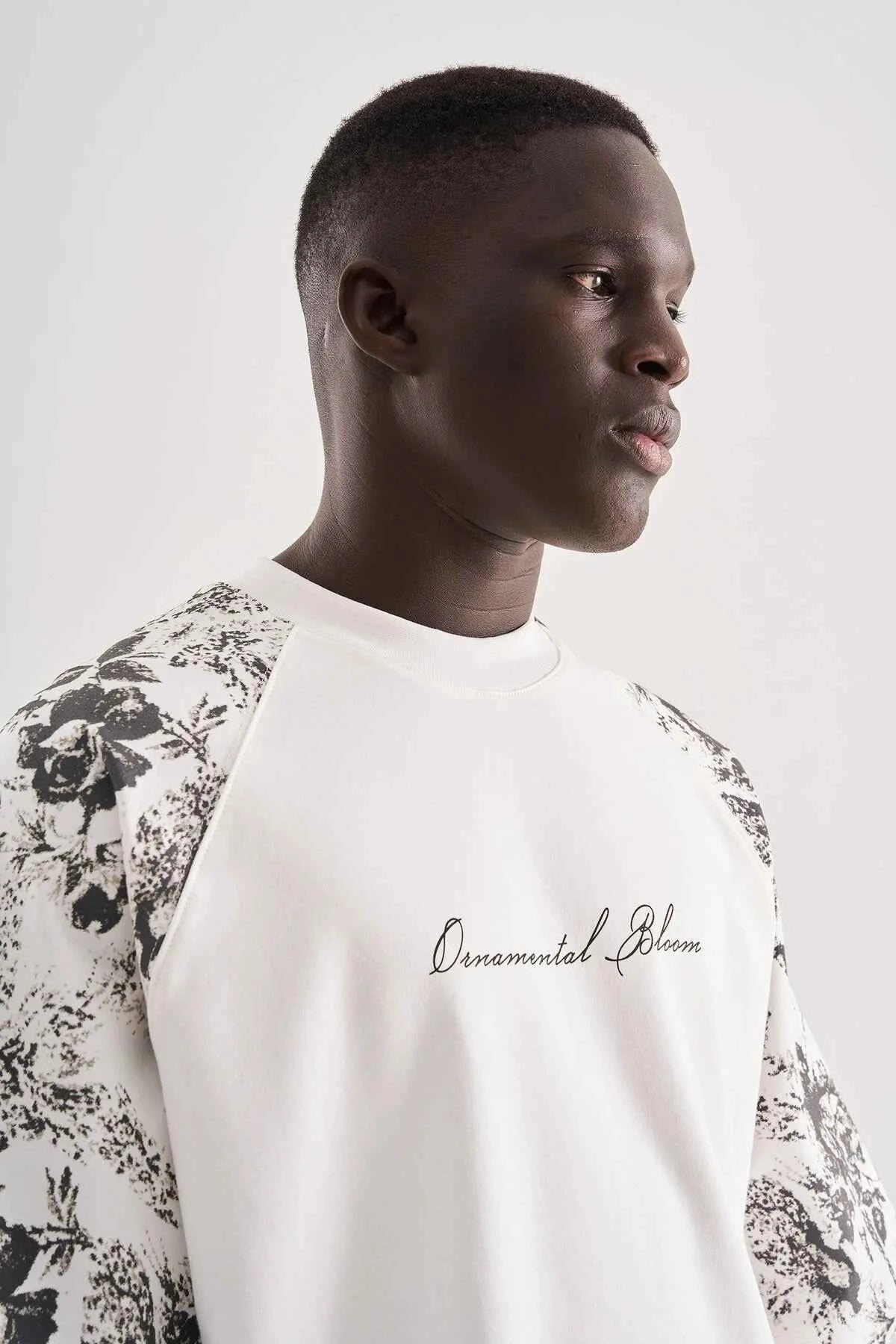 White oversized T-shirt in profile with black floral shoulder print and chest text