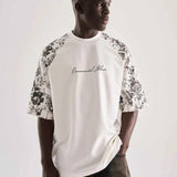 White oversized T-shirt with black floral print sleeves and FLW logo