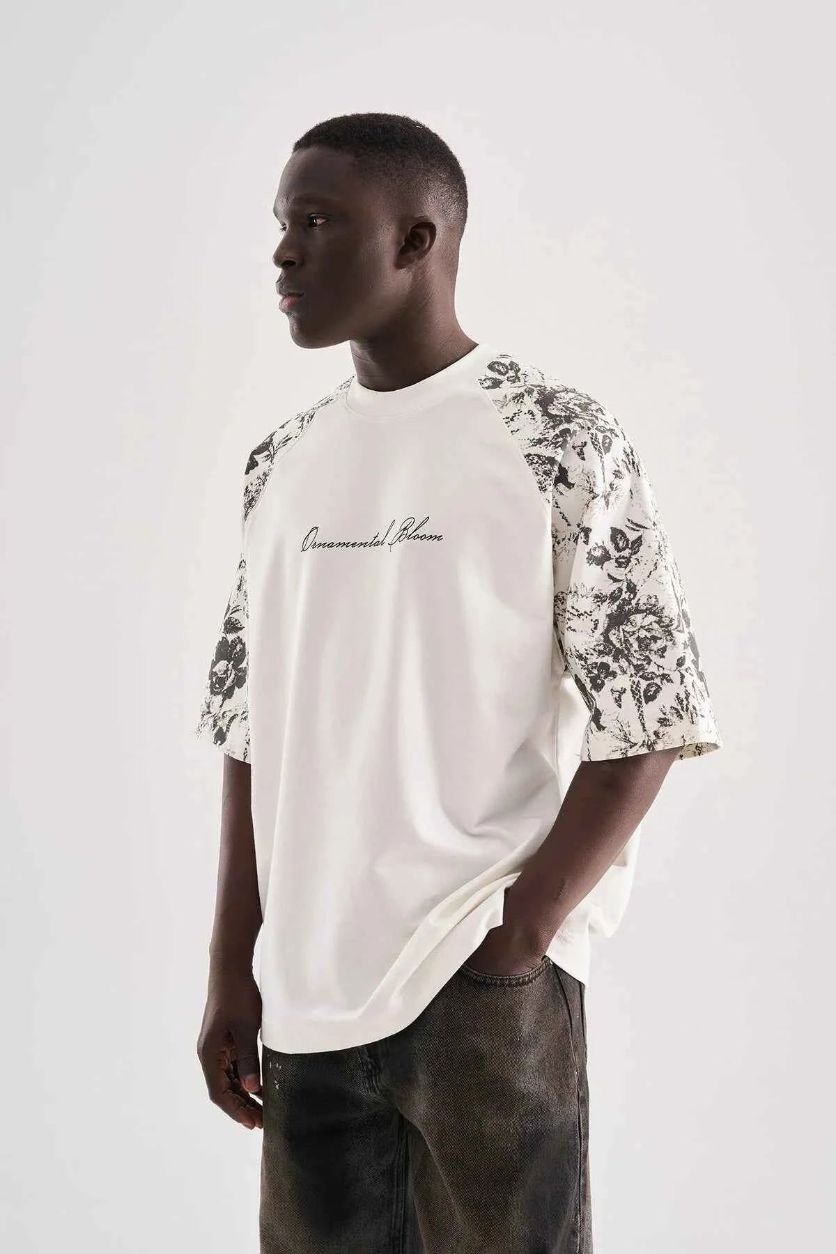 White oversized T-shirt with black floral sleeve print and draped front hem