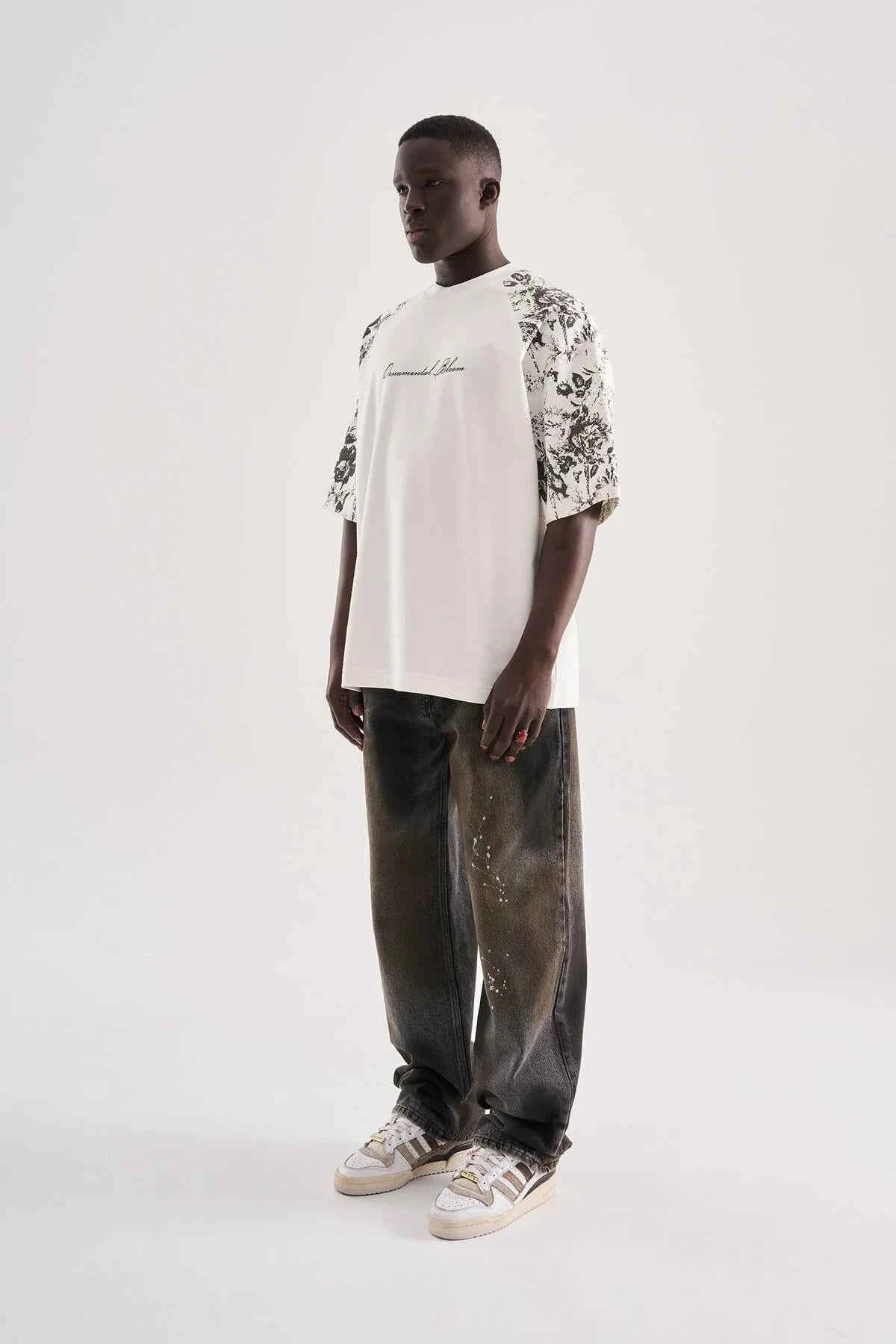 White oversized T-shirt with black floral sleeve print, side view
