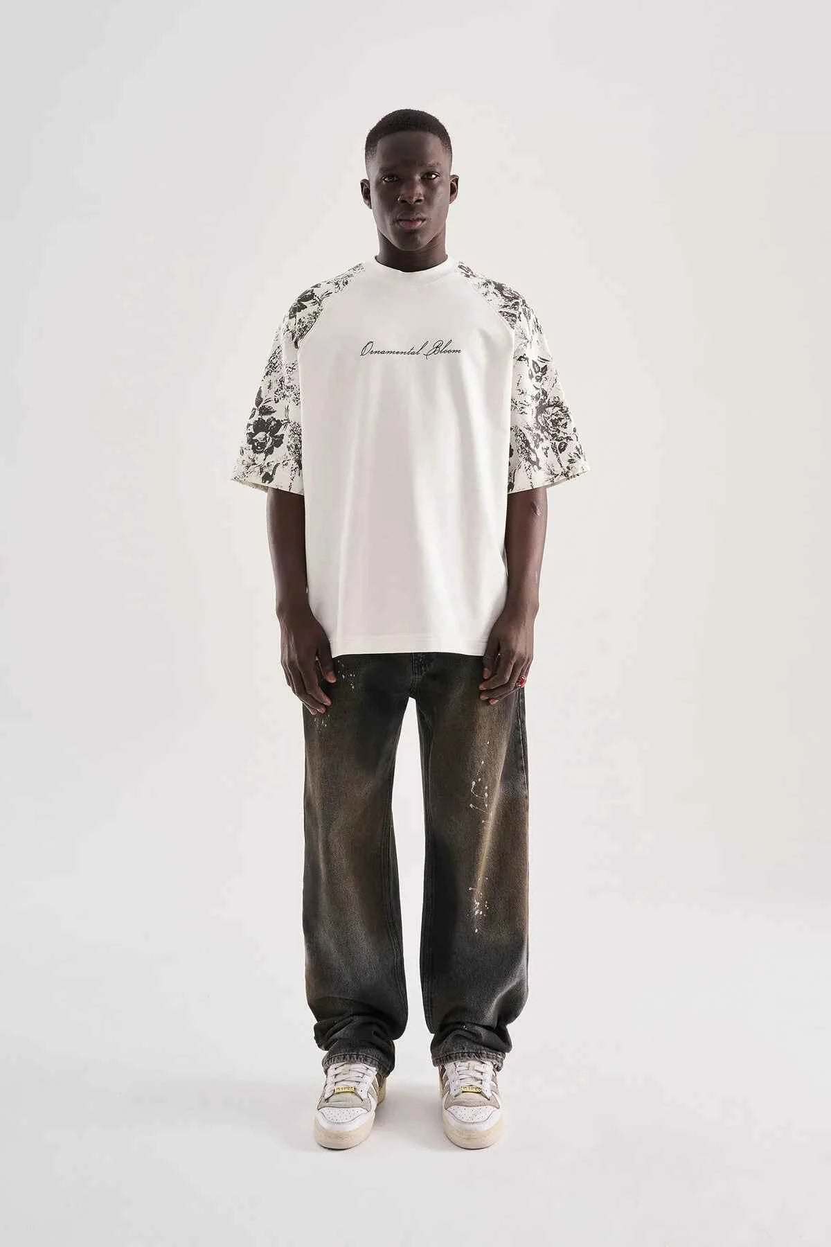 White oversized T-shirt with black floral print sleeves and center chest cursive text