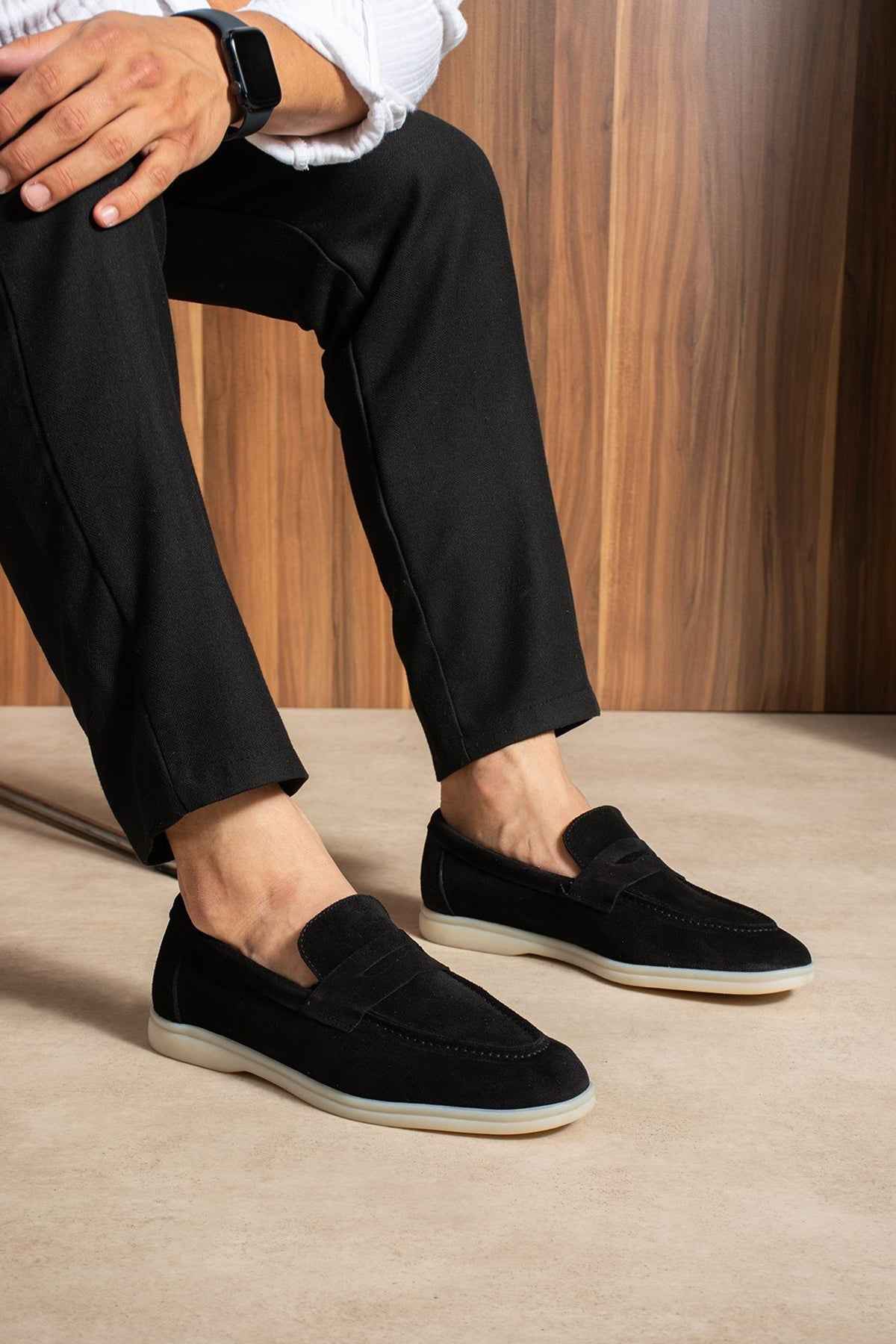 Black slip-on loafers with strap detail and white rubber sole