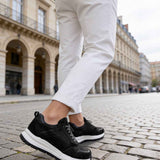 Men's black leather lace-up sneakers with white sole, walking stance