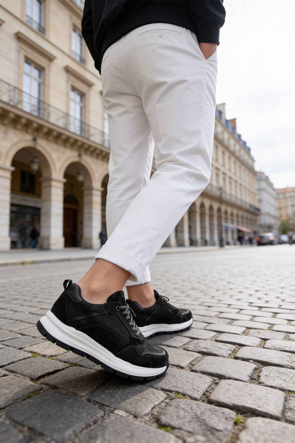 Men's black leather lace-up sneakers with white sole, walking stance