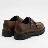 Brown leather double-buckle loafers shown from heel, black outsole