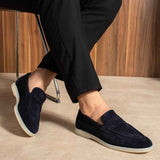 Navy leather loafers on feet with low heel and white rubber outsole