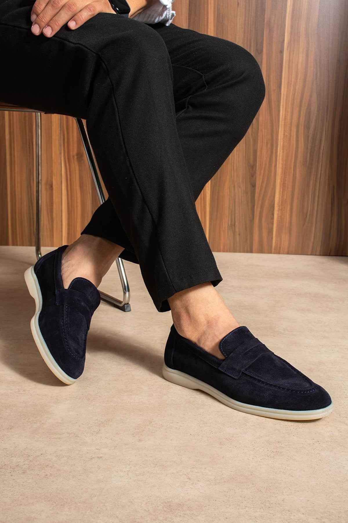Navy leather loafers on feet with low heel and white rubber outsole