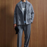 Gray oversized double-breasted coat with notch lapels, black button closure, flap pockets
