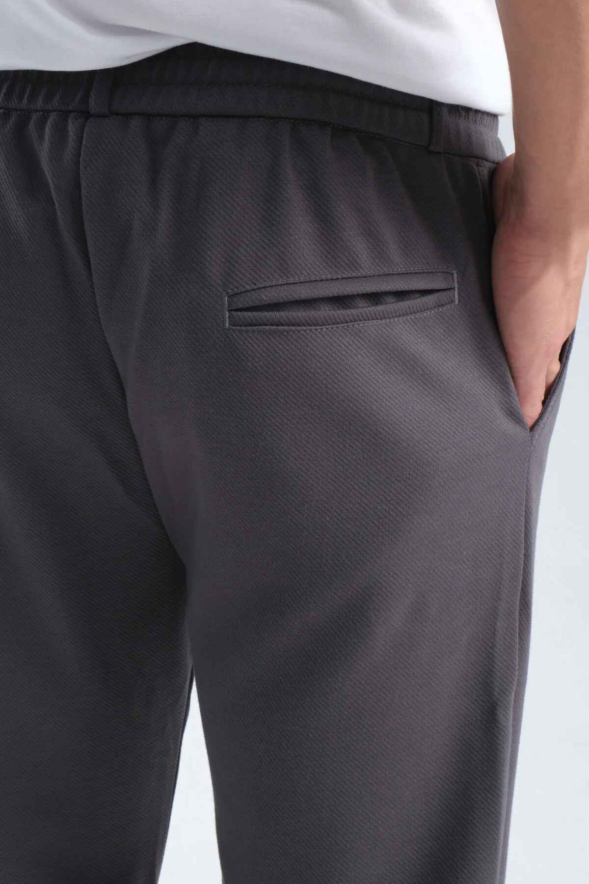 Men's gray sweatpants, back pocket and waistband hem close-up