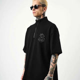 Men's black oversize half-zip T-shirt with small embroidered chest logo, front view.