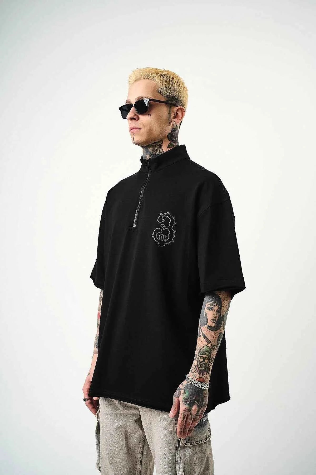 Men's black oversize half-zip T-shirt with small embroidered chest logo, front view.
