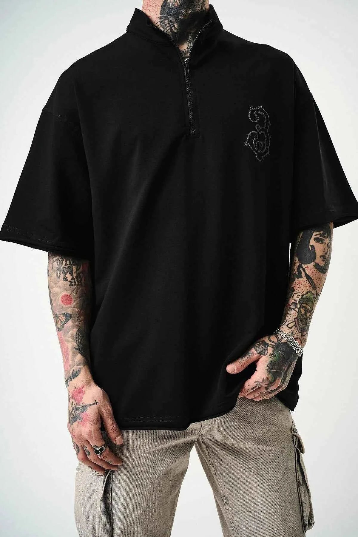 Men's black oversize half-zip T-shirt with embroidered chest logo, quarter front.