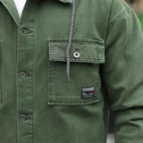 Olive denim jacket chest pocket with flap, button, and hanging chain detail