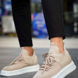 Beige knit lace-up sneakers with white sole, side view with dark pants