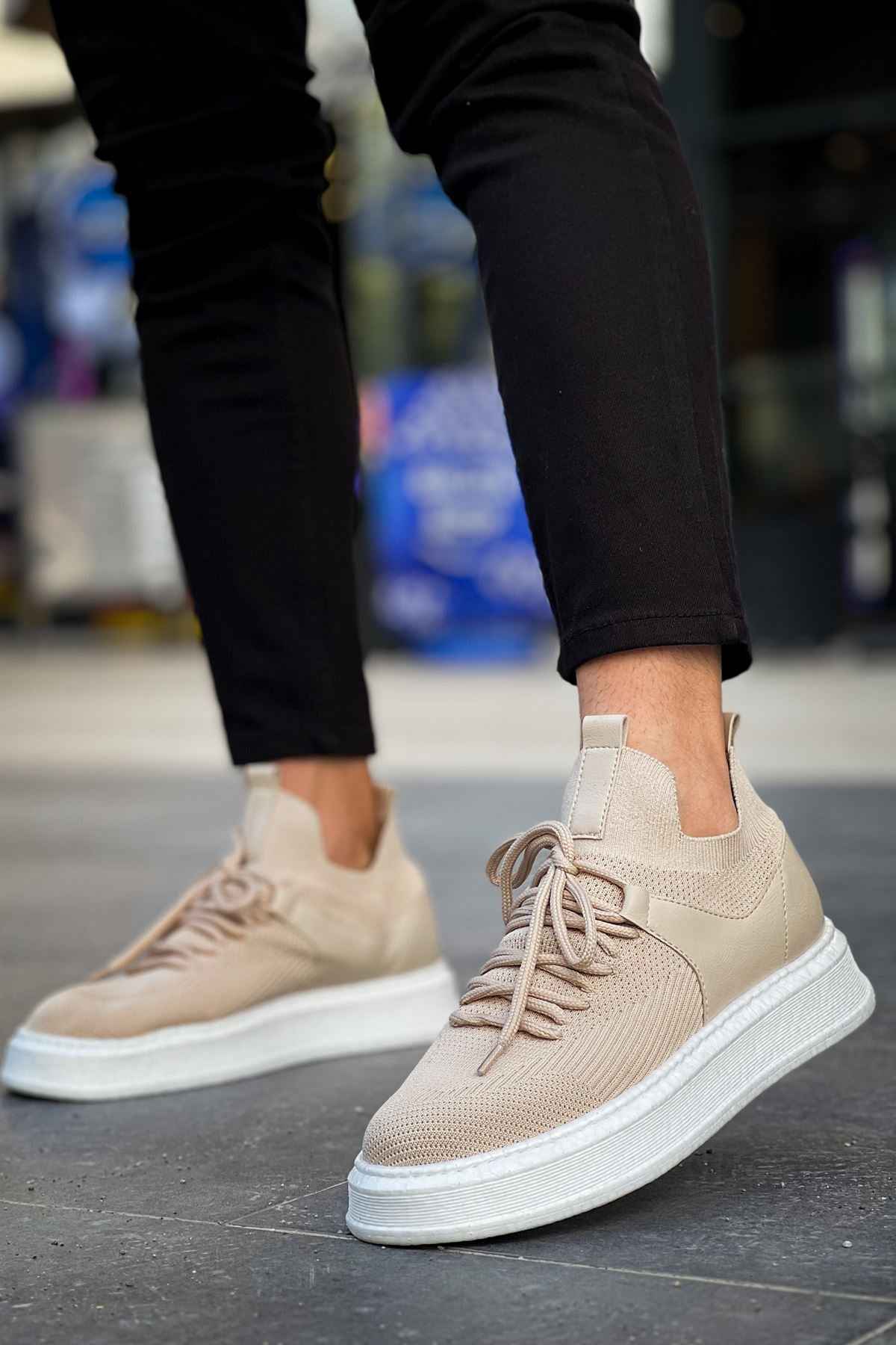 Beige knit lace-up sneakers with white sole, side view with dark pants