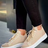 Beige knit sneakers with lace-up front and white rubber sole, angled