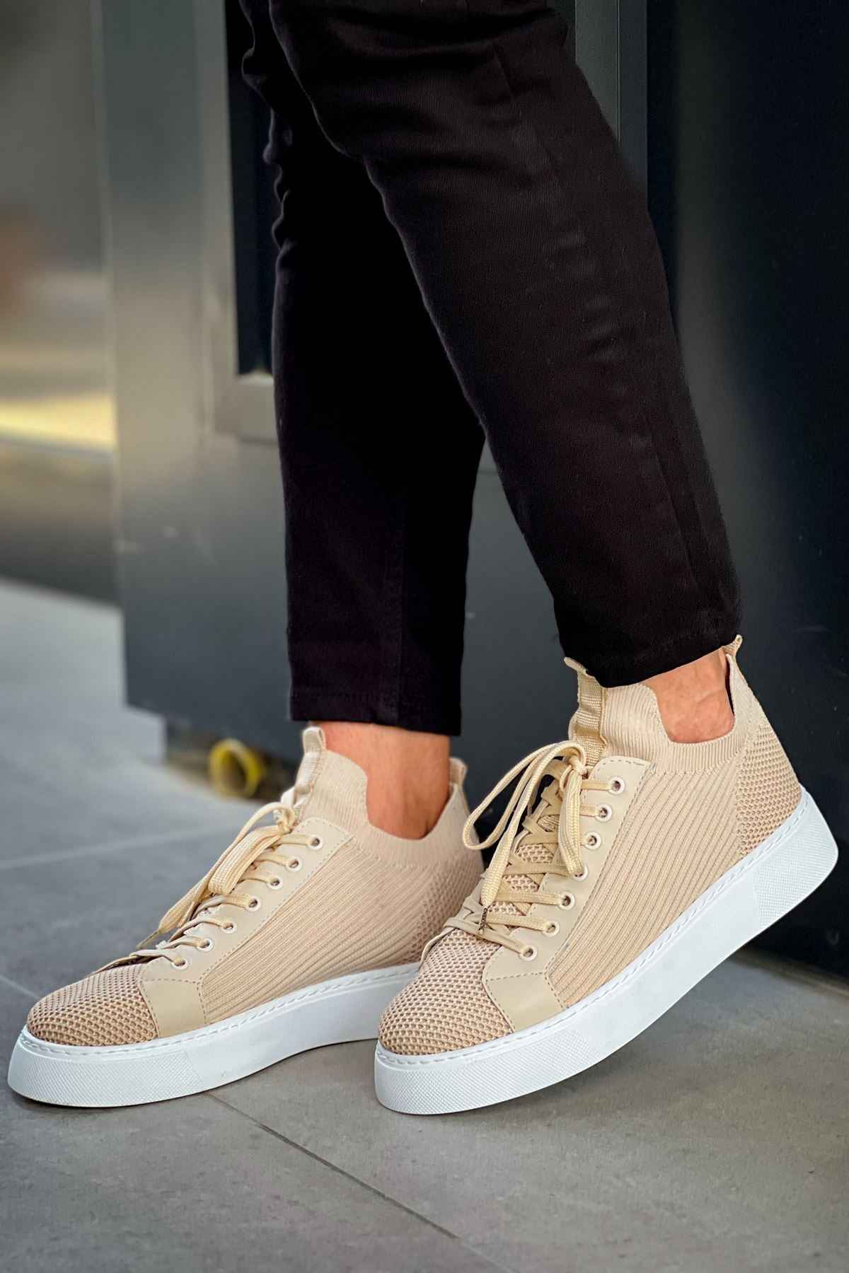 Beige knit sneakers with lace-up front and white rubber sole, angled
