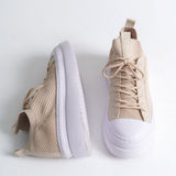 Pair of men's beige knit sneakers with white sole, shown from the side