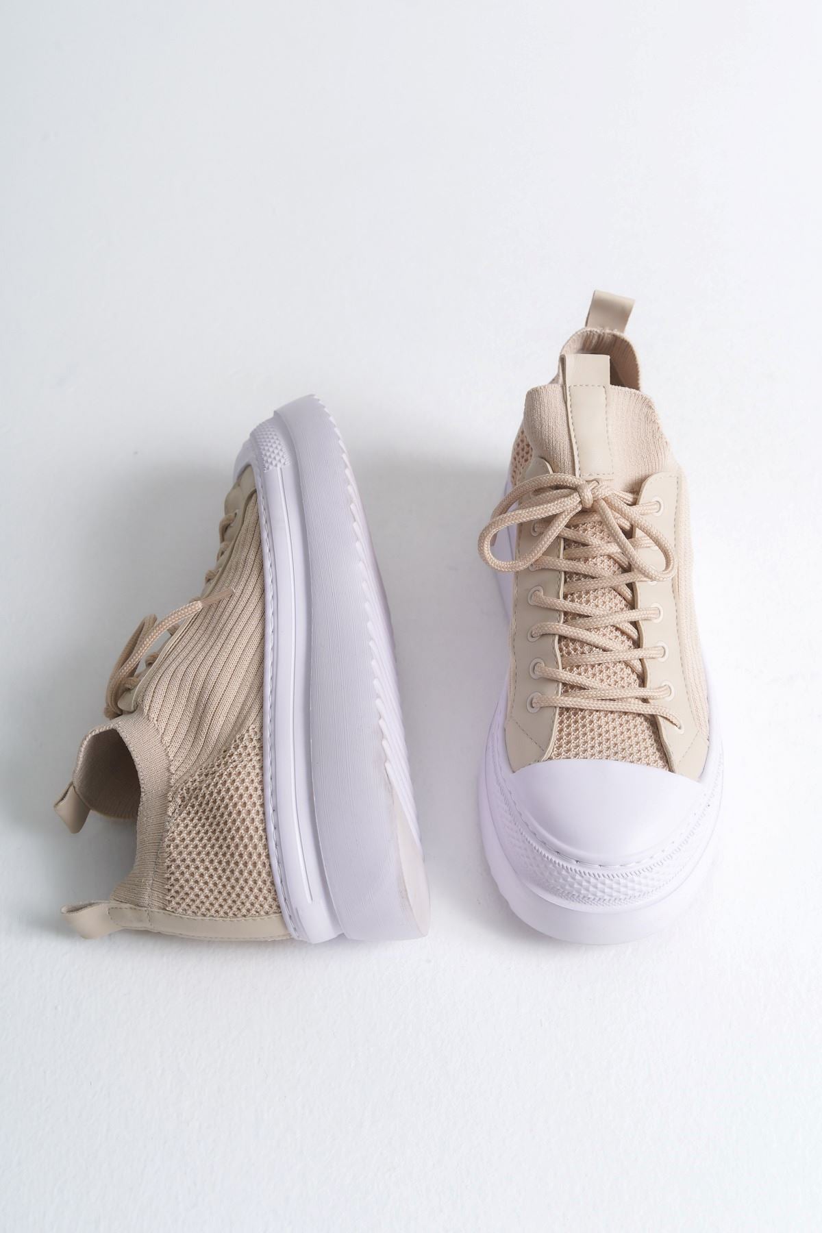 Pair of men's beige knit sneakers with white sole, shown from the side
