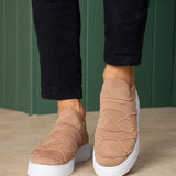 Beige knit sneakers with white soles, cushioned heel and stitched side pattern