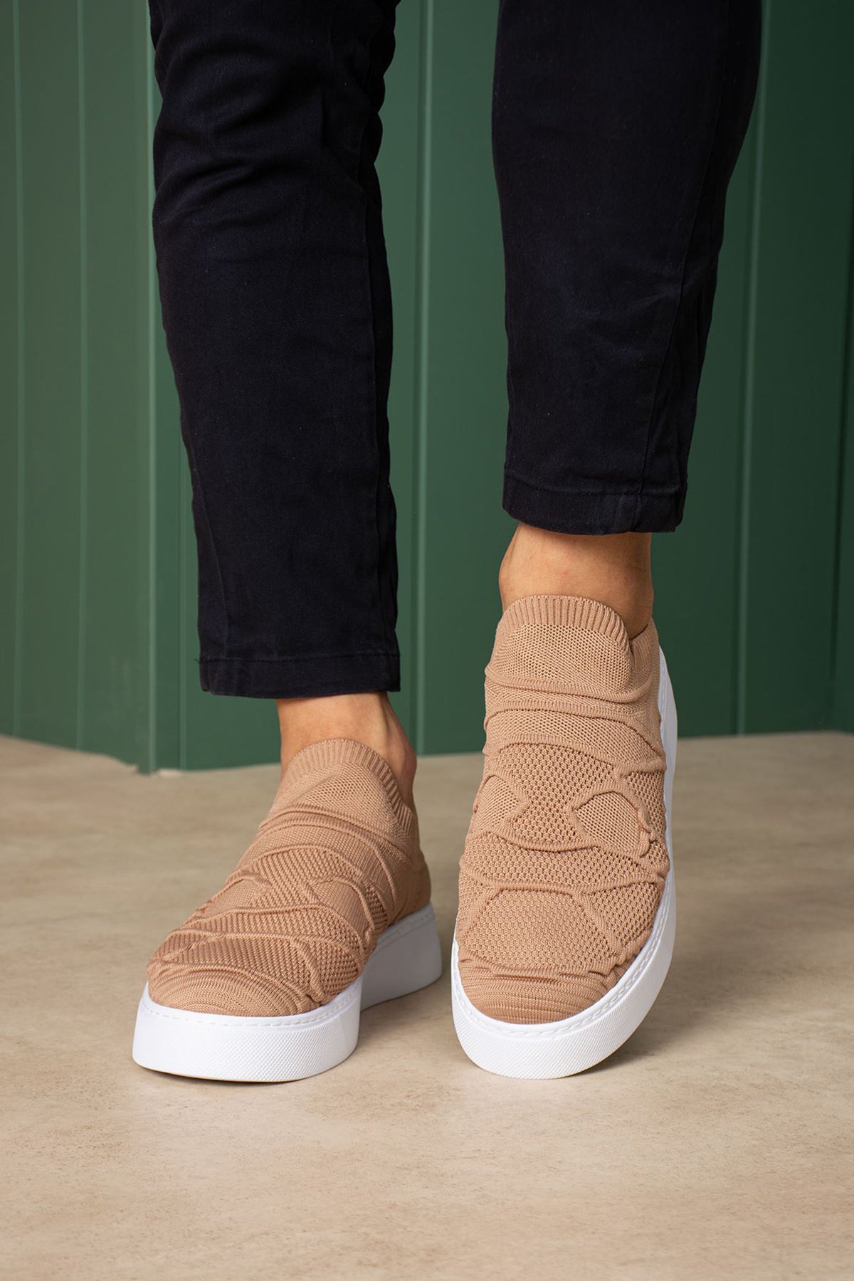 Beige knit sneakers with white soles, cushioned heel and stitched side pattern