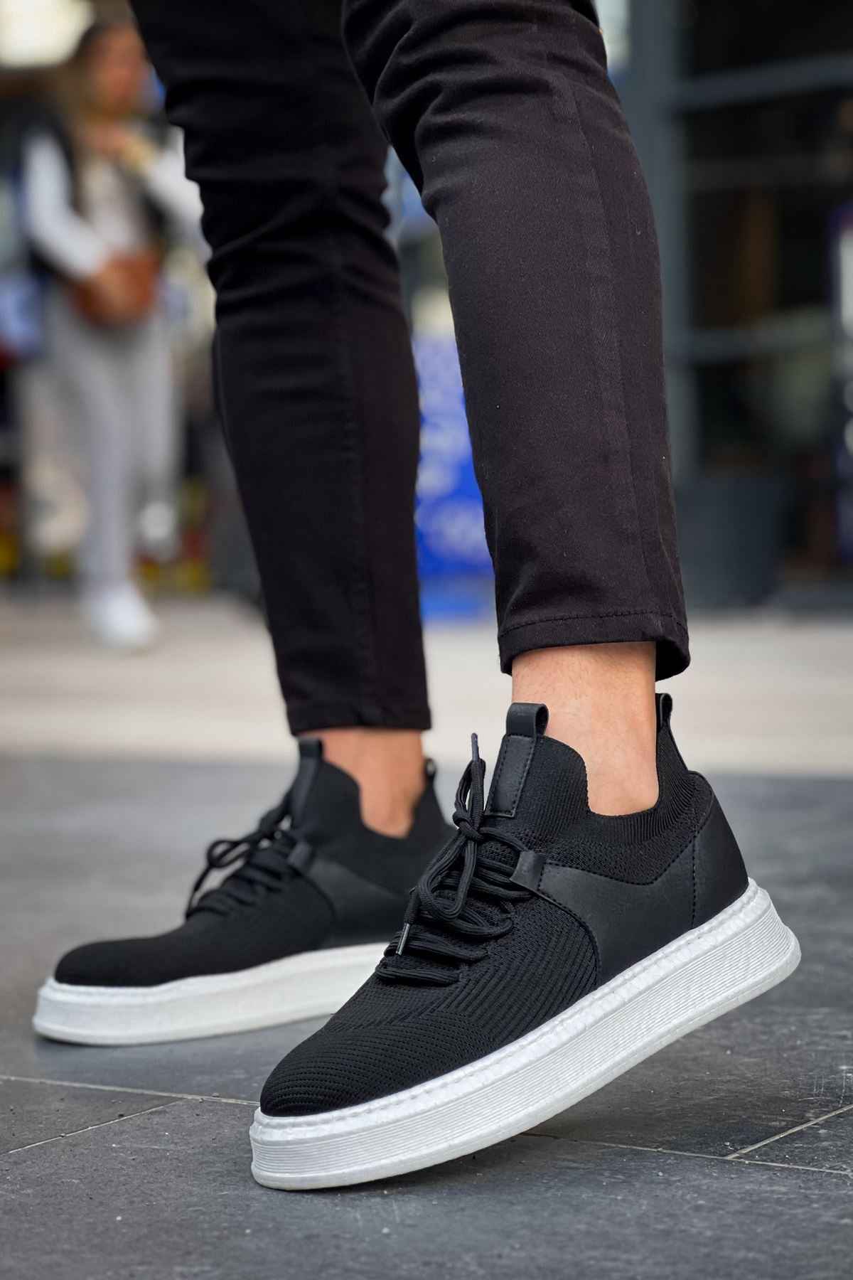 Black knit lace-up sneakers with white rubber sole, side view.