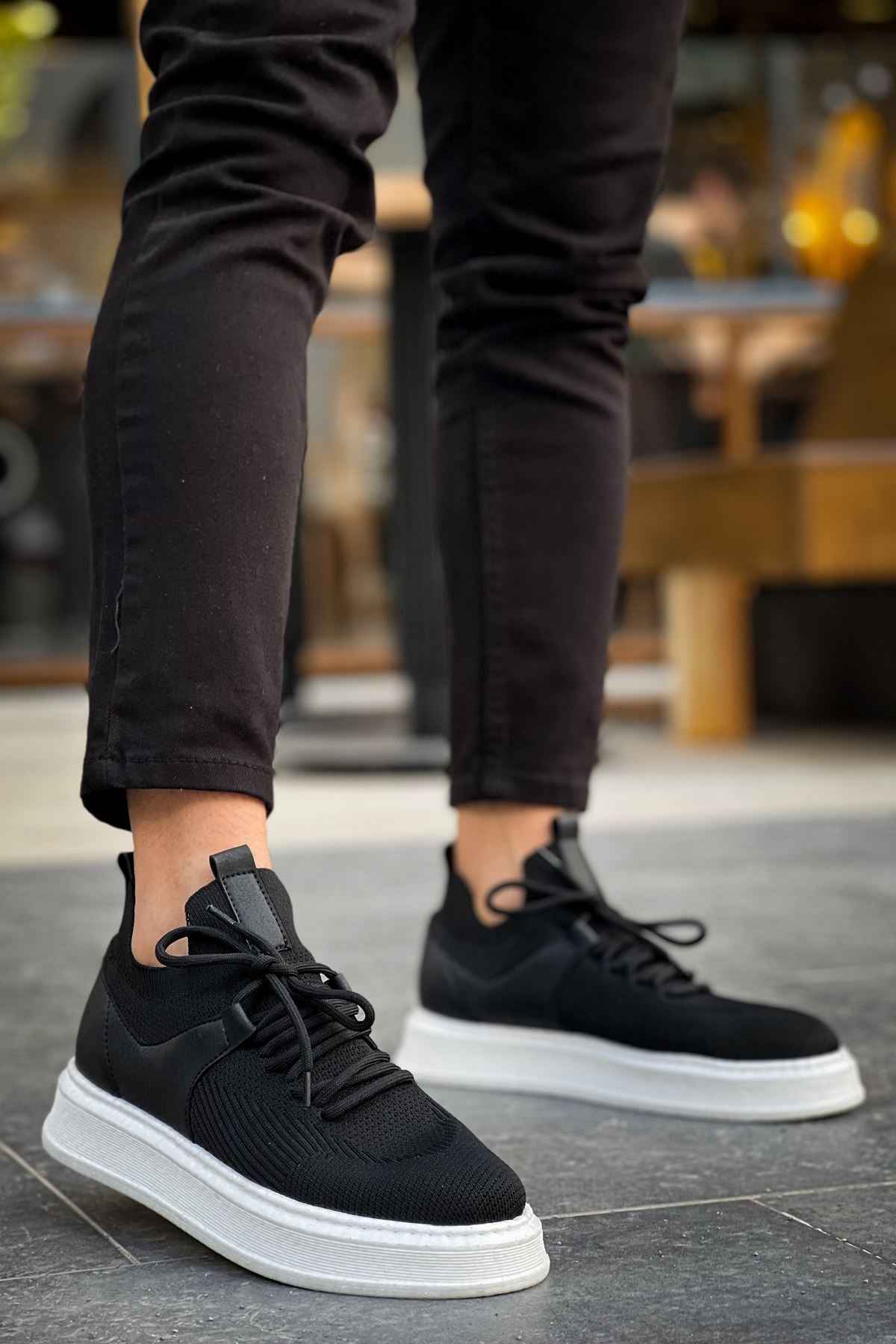 Black knit lace-up sneakers with white sole, side profile.