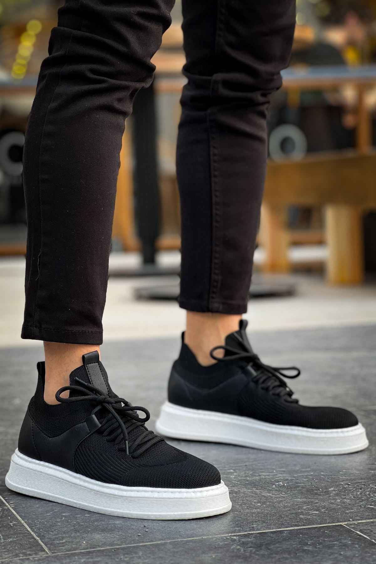 Black knit lace-up sneakers with white sole, front angle.