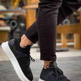 Black knit lace-up sneakers with white sole, stepping view.