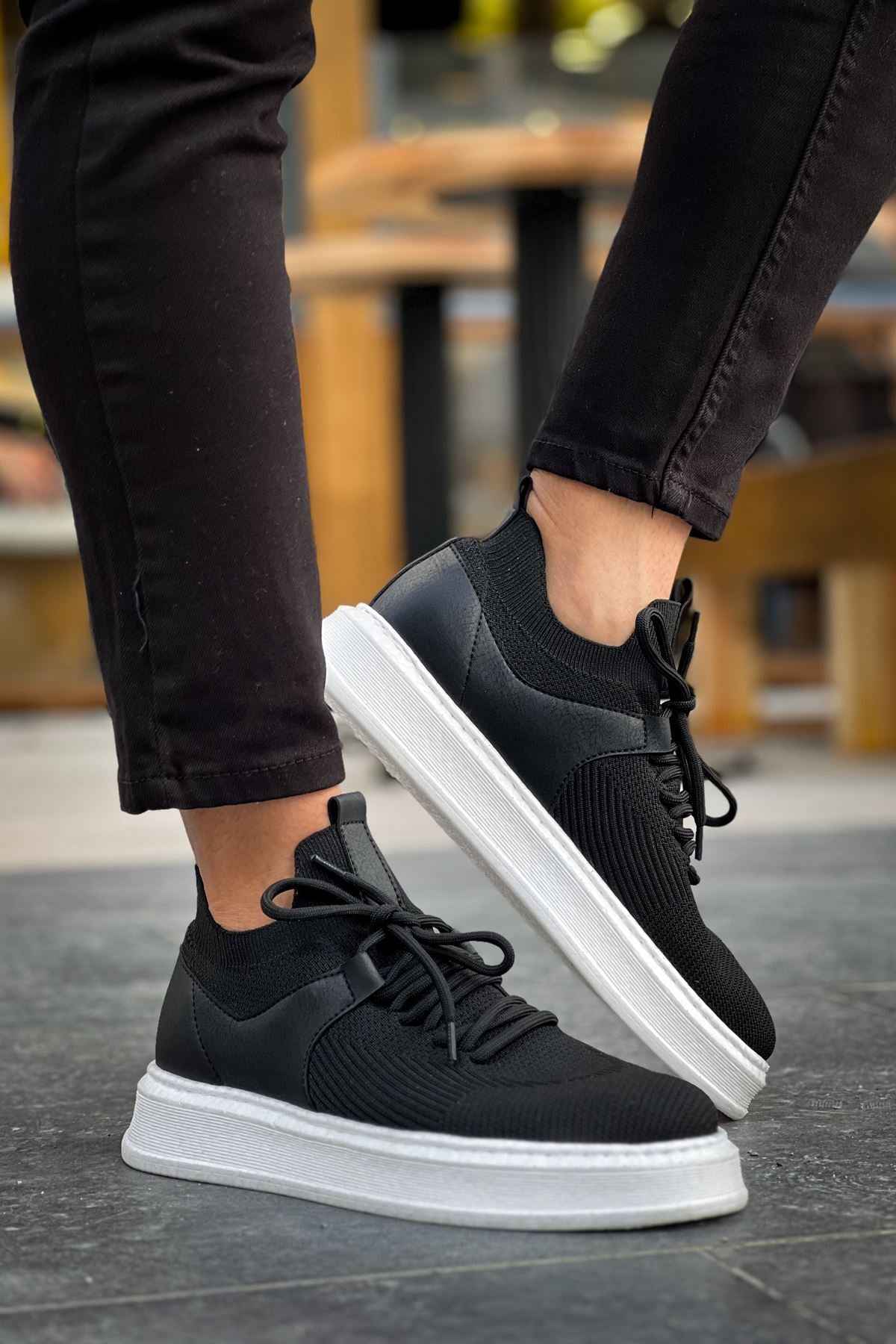 Black knit lace-up sneakers with white sole, close side view.