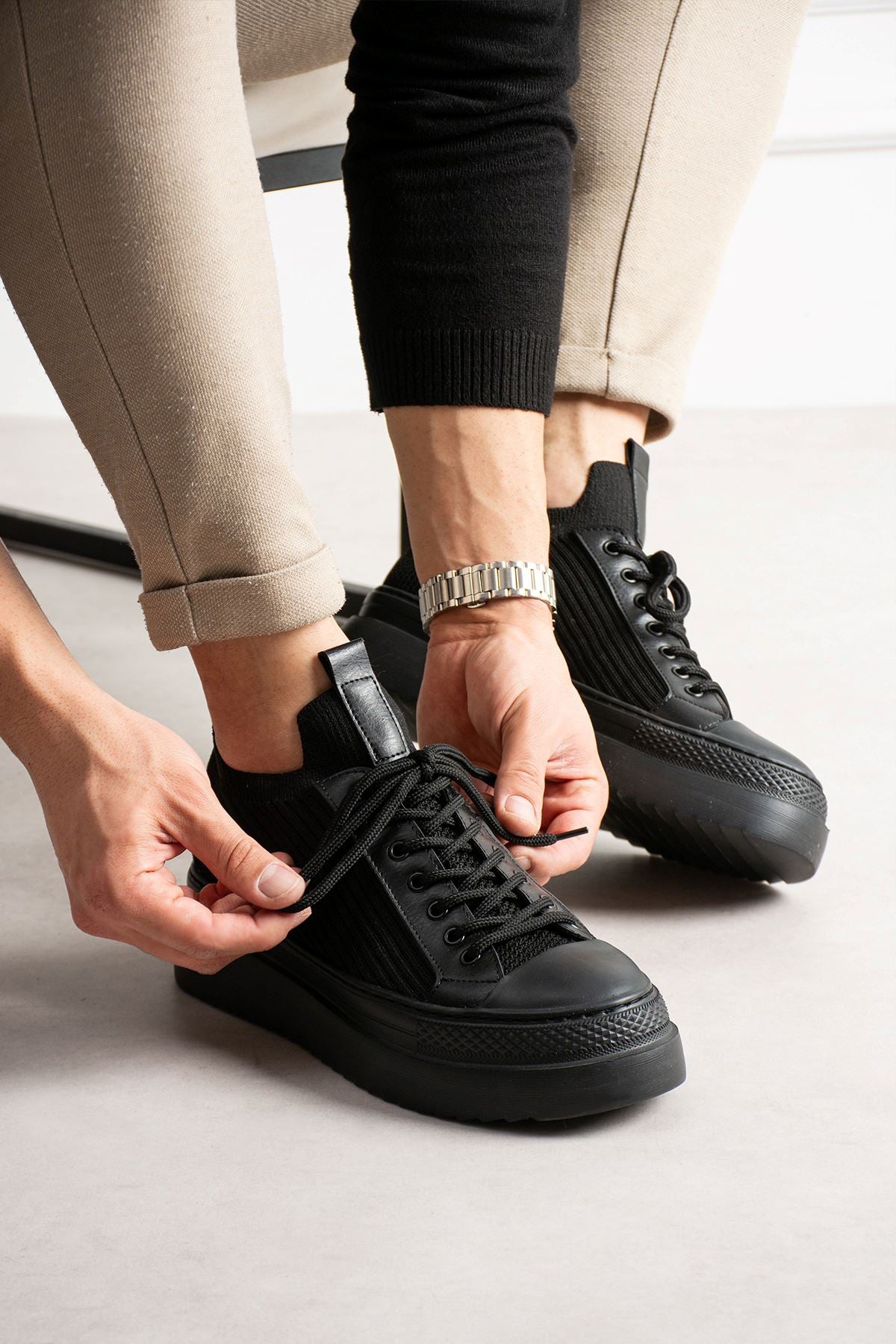 Black knit lace-up sneakers with perforated toe and textured side panels