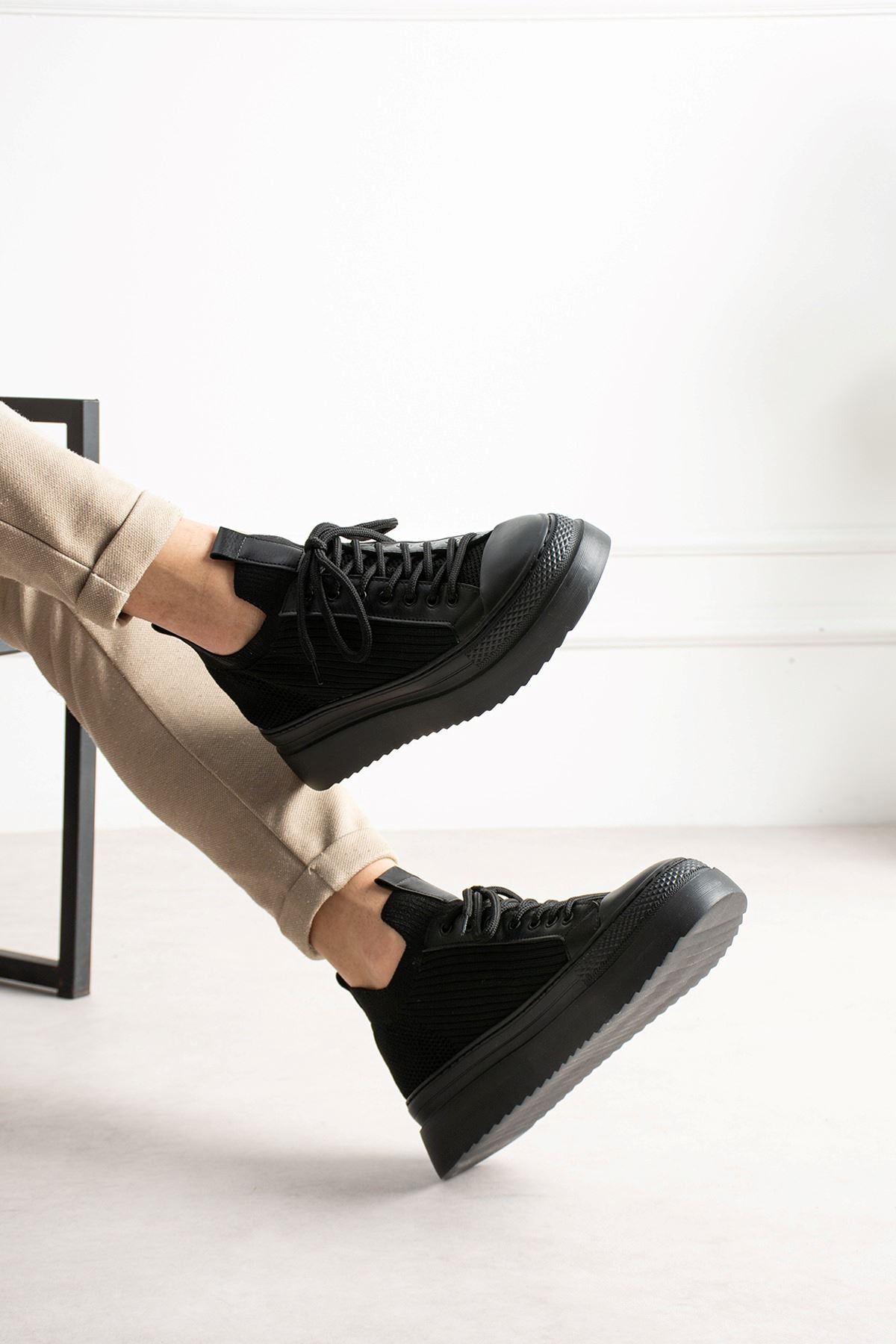 Black knit sneakers with chunky outsole, lace-up front, and ankle collar