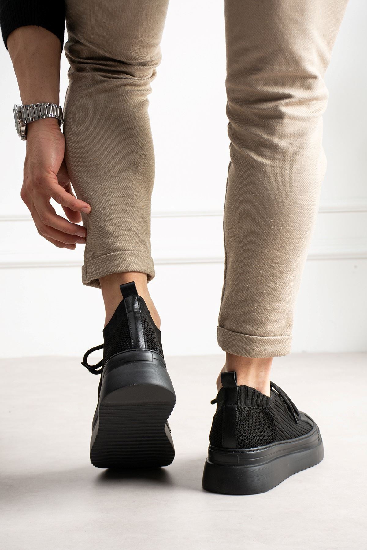 Black knit sneakers with rear pull tab, cushioned collar, and rubber heel