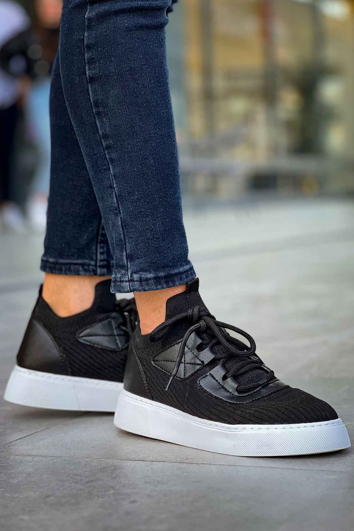 Knit black sneakers with lace-up front, white rubber sole, and side panel design