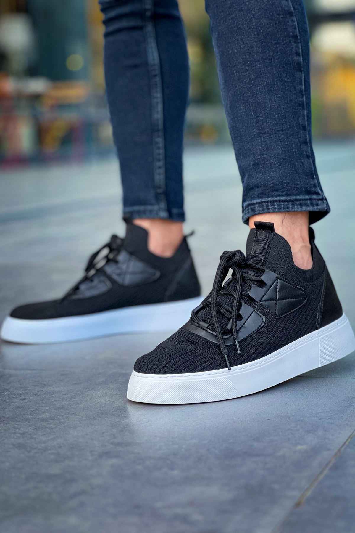 Low-top black knit sneakers with black laces and white sole, toe and side view
